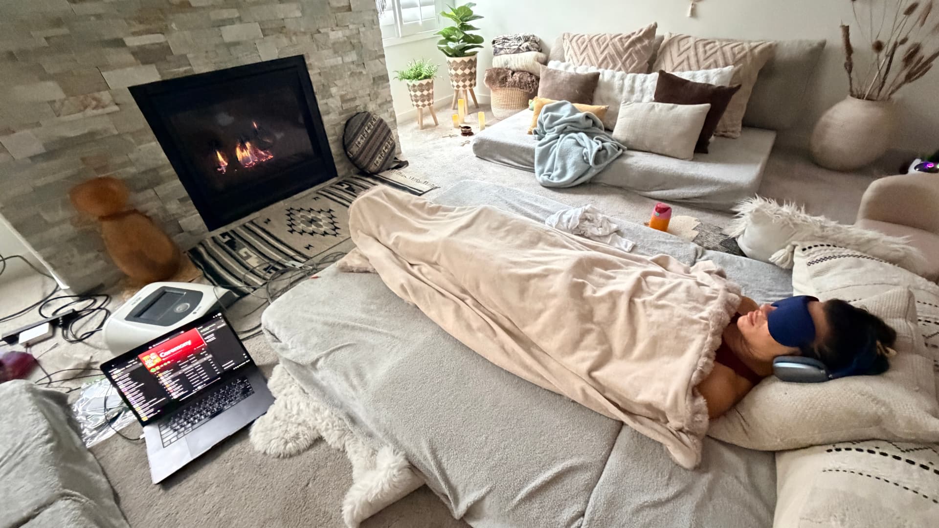 Client resting under blankets by the fire during a guided breathwork journey